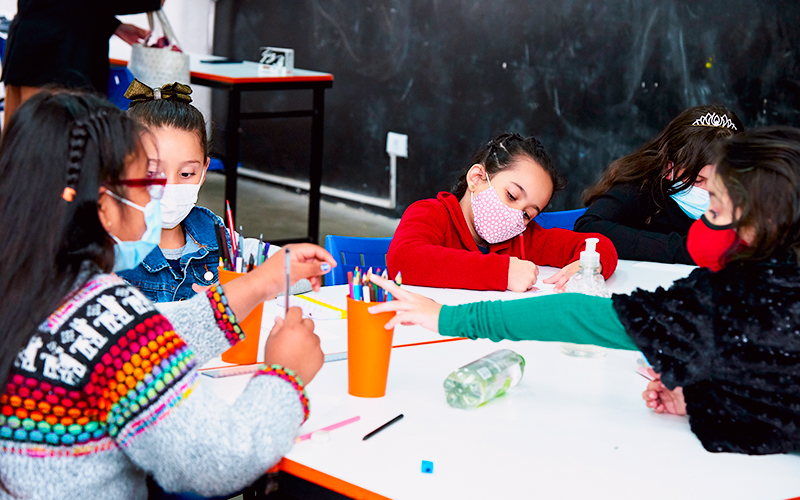 Fotografaria de crianças em uma sala de aula fazendo atividade com lápis de cor