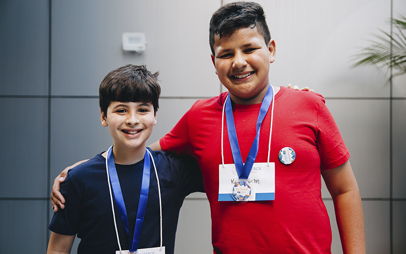 Fotografia de dois alunos Alicerce com medalhas da competição: soletrando Alicerce