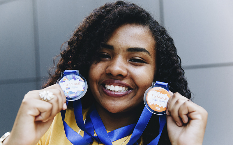 Fotografia de aluna Alicerce segurando medalhas da competição: soletrando Alicerce