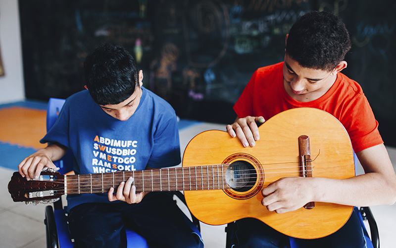 Fotografia de dois alunos Alicerce tocando violão