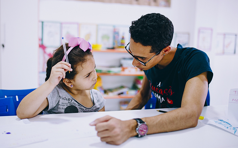 Fotografia de um educador Alicerce explicando o conteúdo para a aluna